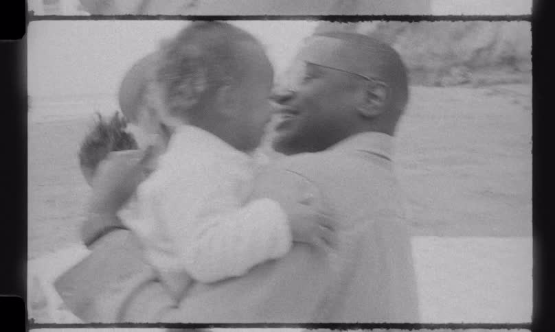 A loving family laughs and enjoys a picnic on the beach in this nostalgic, black and white old film footage