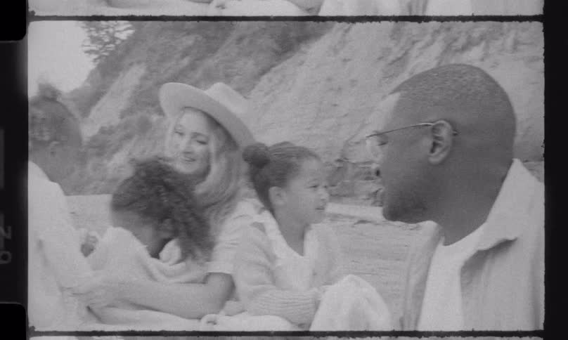 A loving multiracial family with three young children enjoys a happy day at the beach in this vintage black and white film-style footage