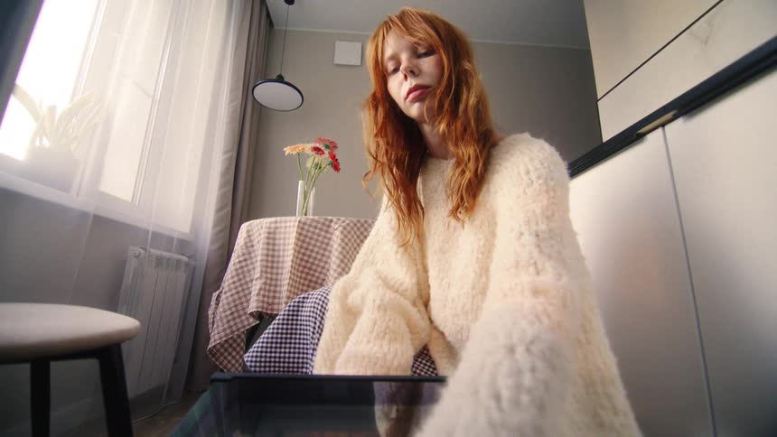 A young woman with long red hair pulls freshly baked bread from the oven, captured in a unique POV shot from inside