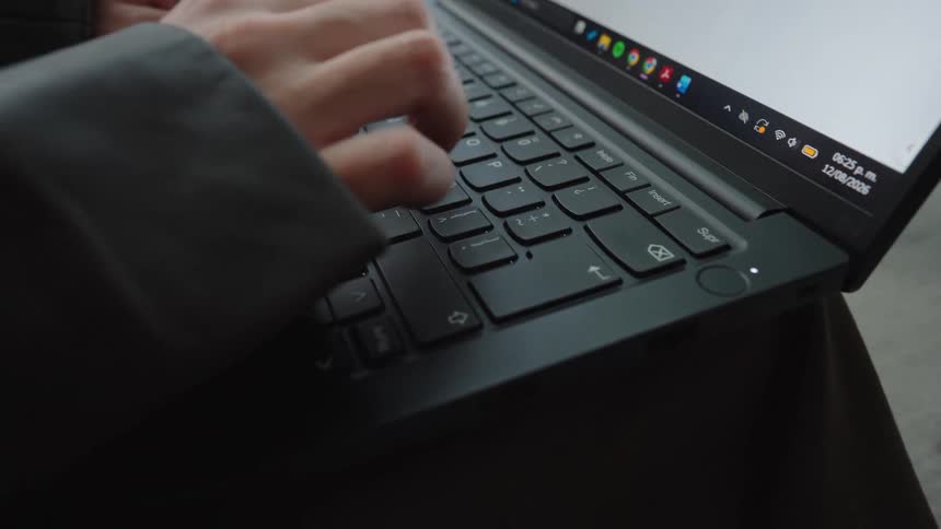 Close-up of a person in a blazer diligently typing on a sleek, modern laptop keyboard