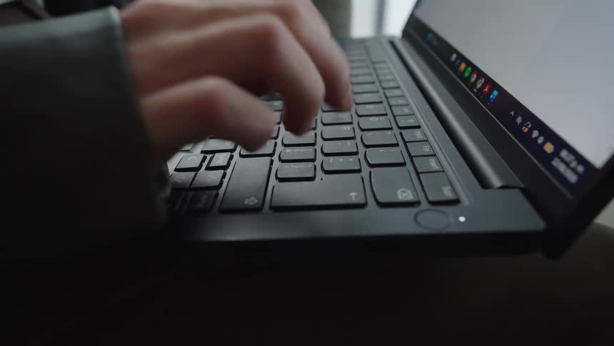 Close up of a professional typing on a laptop keyboard in a modern apartment