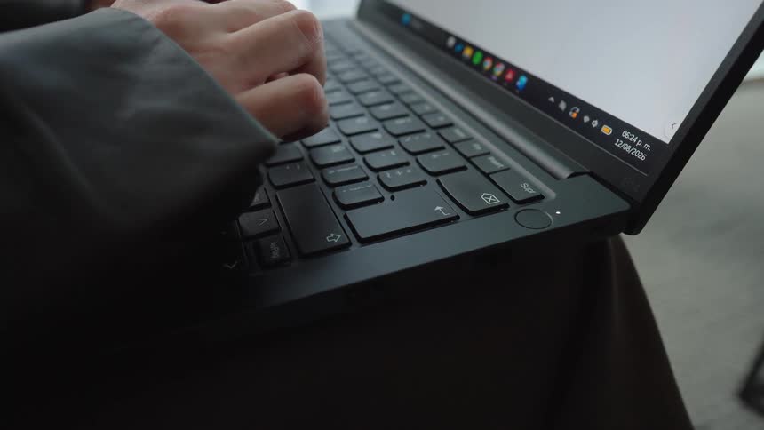 A close-up, slow push-in shot of hands typing on a sleek black laptop keyboard