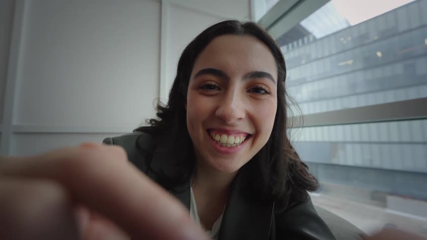 Point of view of a smiling young woman happily swiping and browsing on her device while indoors