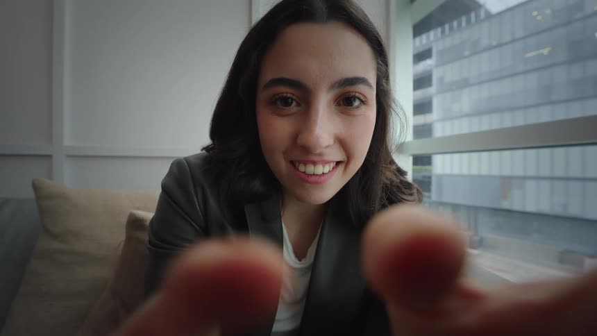 Cinemagraph loop of a happy young woman looking directly into the camera from a close-up POV perspective in a modern apartment