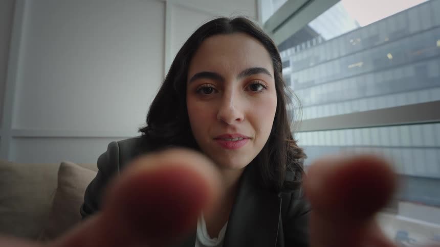 Intimate point-of-view shot of a young woman looking into the camera with a serious face that slowly breaks into a genuine, happy smile