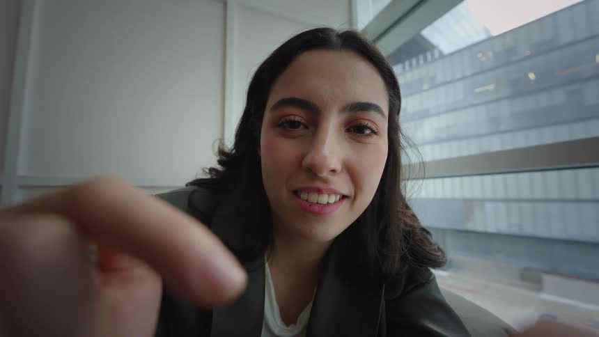 POV cinemagraph of a smiling young woman scrolling through her phone in a modern city apartment