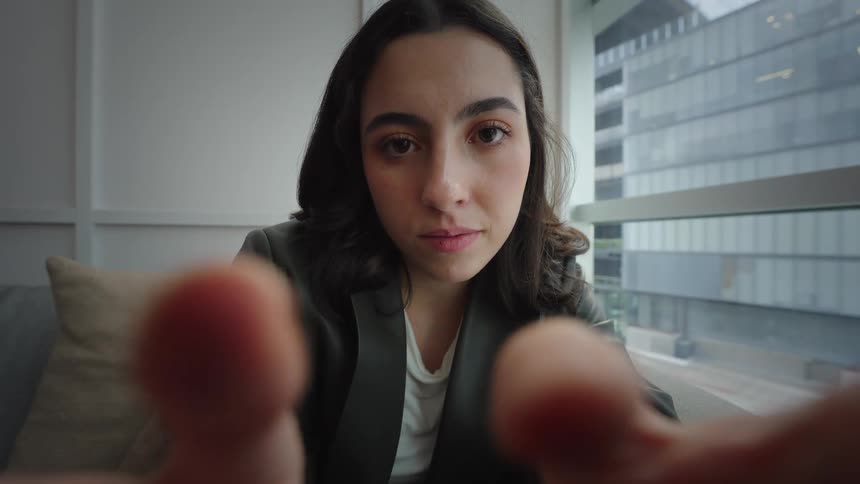 POV cinemagraph of an intense young woman staring into the camera with her out-of-focus fingers moving in the foreground