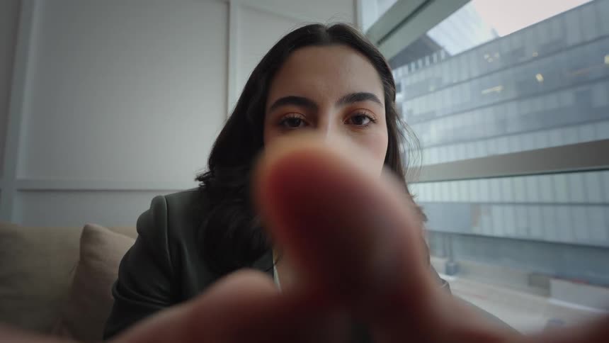 POV cinemagraph of a young woman looking at her phone's screen with her fingers framing the shot