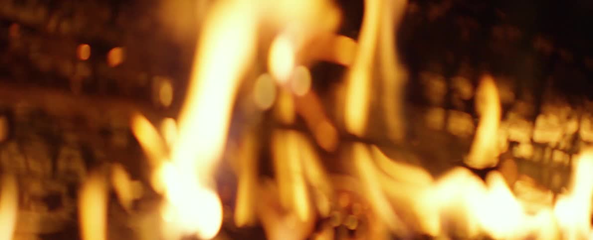 A mesmerizing close-up of a campfire in slow motion, slowly going out of focus into a warm, abstract blur