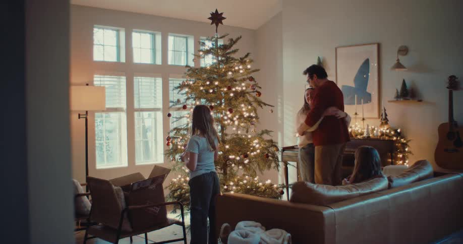A family of four shares a joyful moment while decorating their Christmas tree for the holidays