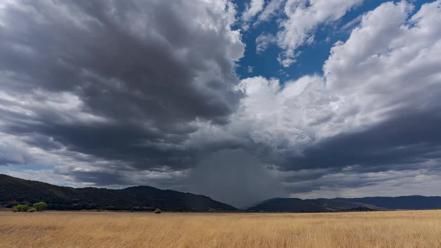 A powerful storm cell unleashes a concentrated downpour over a mountain valley in this dramatic time-lapse
