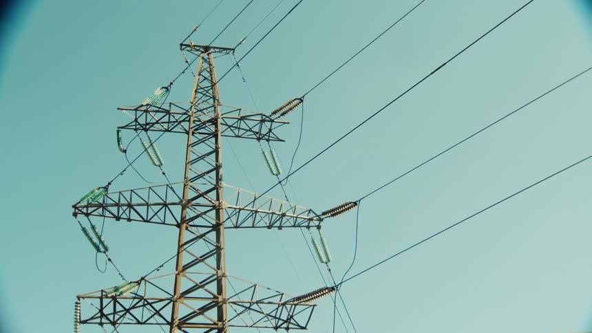 Observing a metal electricity pylon and power lines against a clear blue sky through a circular vignette