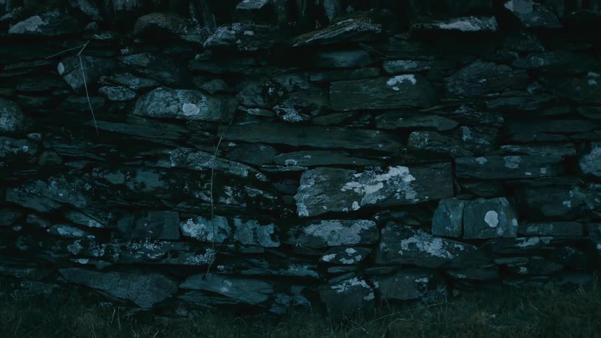 An old, weathered dry stone wall sits in the darkness