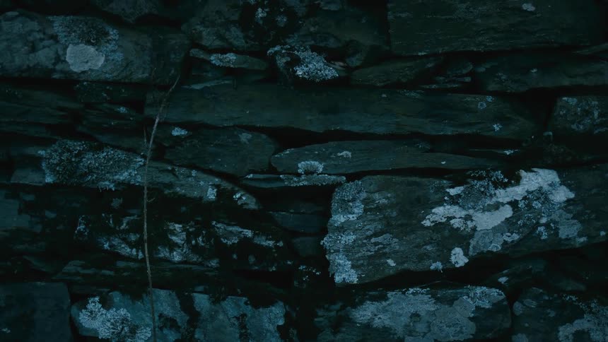 A creepy close up of an old stone wall at night with a subtle light flicker