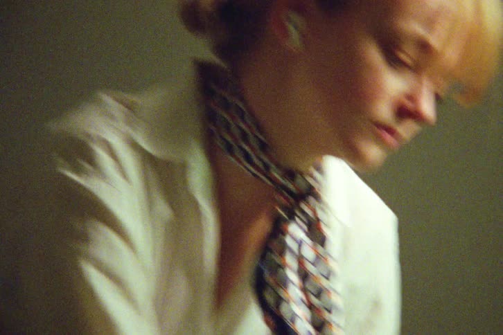 Close-up handheld shot of a young stylish woman listening to music on earbuds as she packs and closes her suitcase