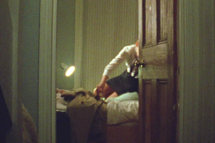 A young girl in a school uniform sneaks into a dimly lit bedroom and steals a wallet from a sleeping person