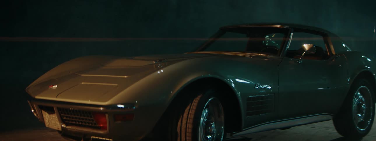 A cinematic close-up of a vintage American muscle car parked in a dark, moody setting