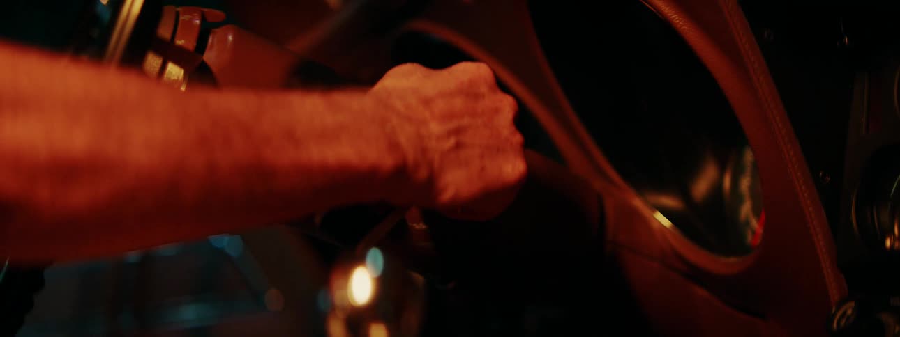 Moody close-up shot of a hand turning the key to start the engine of a vintage automobile