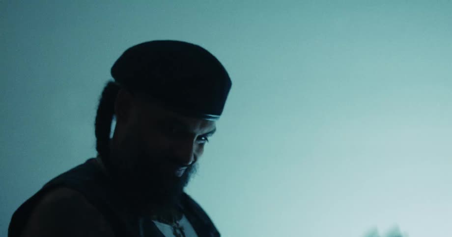 A stylish man with a beard and beret counts a large stack of cash in a cool, backlit studio