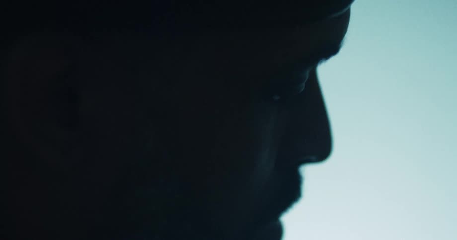 Extreme close-up profile silhouette of a man's face against a bright background