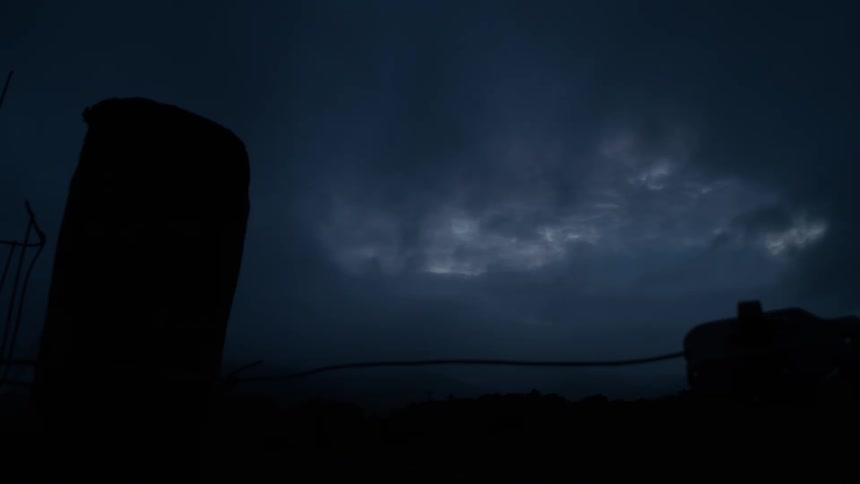 Dark, stormy clouds move across the night sky in a moody low-light scene