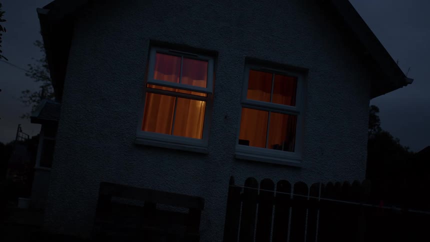 The windows of a suburban home glow with warm orange light as evening falls