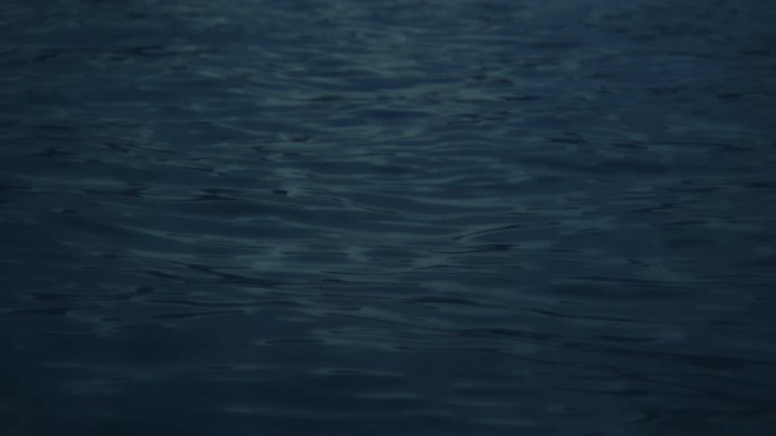 Dark, deep blue water gently ripples across the surface in the low light of night