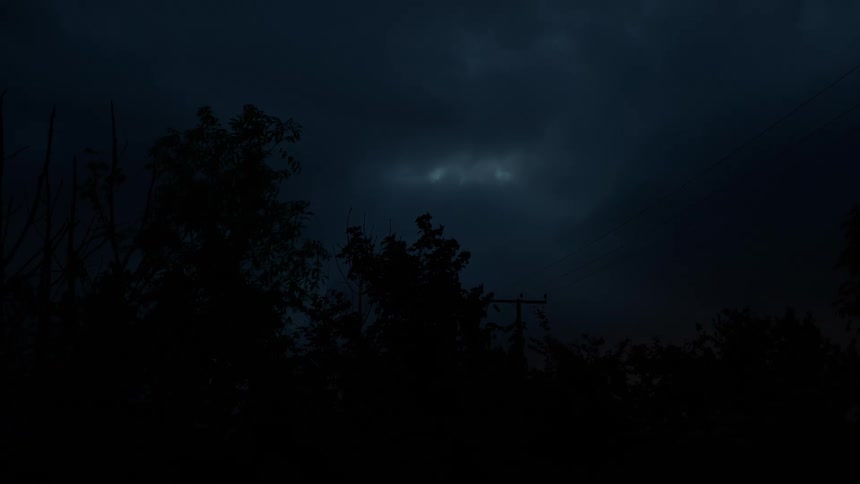 A dark and stormy night sky looms over silhouetted trees as faint lightning flashes within the ominous clouds