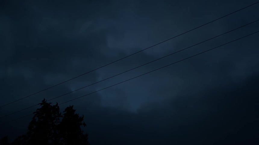Faint lightning flashes within dark storm clouds during a moody night