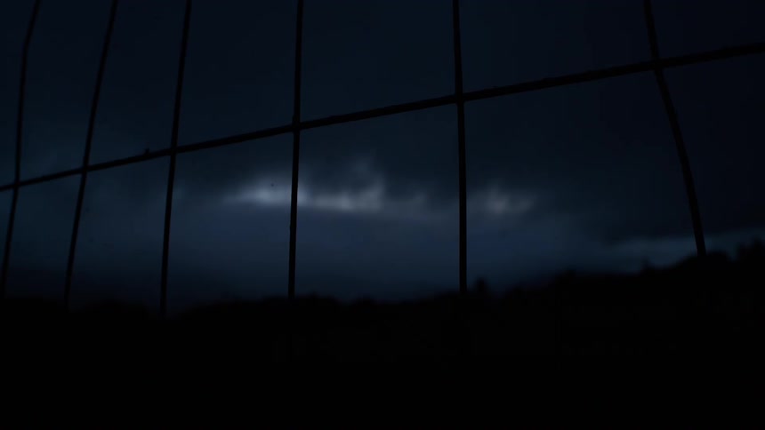 Looking through a rain-streaked window at a dark, stormy night sky