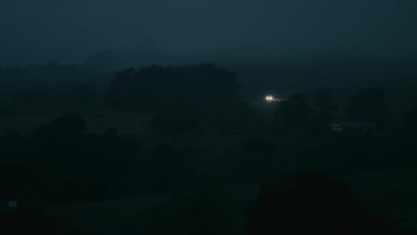 A vehicle's headlights pierce the dark, foggy night as it navigates a rural road and pulls up to a solitary house