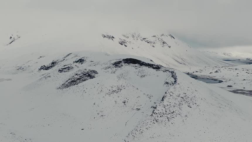 Static view of a vast and desolate snow-covered mountainous landscape on an overcast winter day