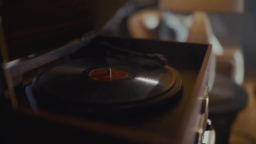 A vintage Victrola record player spins a vinyl record in a dimly lit, atmospheric room