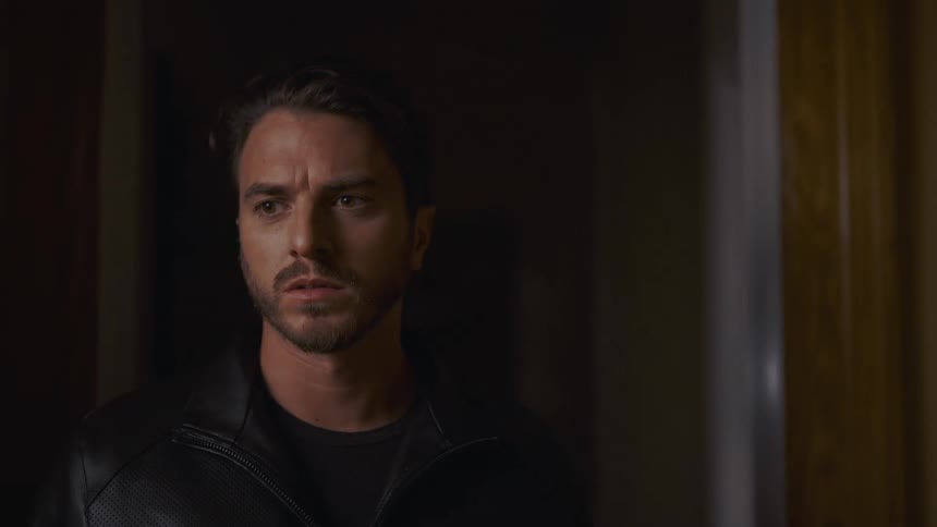 Close-up of a tense man with a worried expression cautiously looking around a dark and mysterious hallway