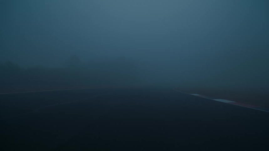 Static shot of an empty race track obscured by thick, dark fog, creating a mysterious and moody atmosphere