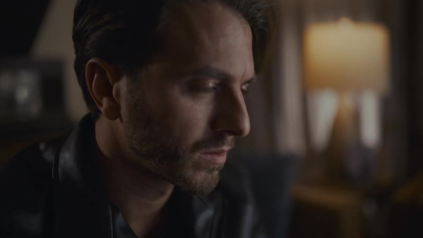Close-up portrait of a thoughtful man with a somber expression in a dimly lit interior