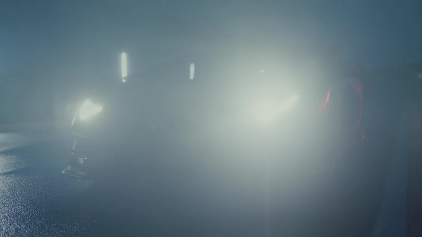 Dramatic shot of a black Lamborghini illuminating a foggy night as its headlights switch on