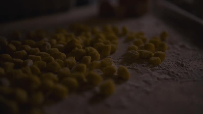 Handmade gnocchi on a rustic wooden board illuminated by shifting sunlight