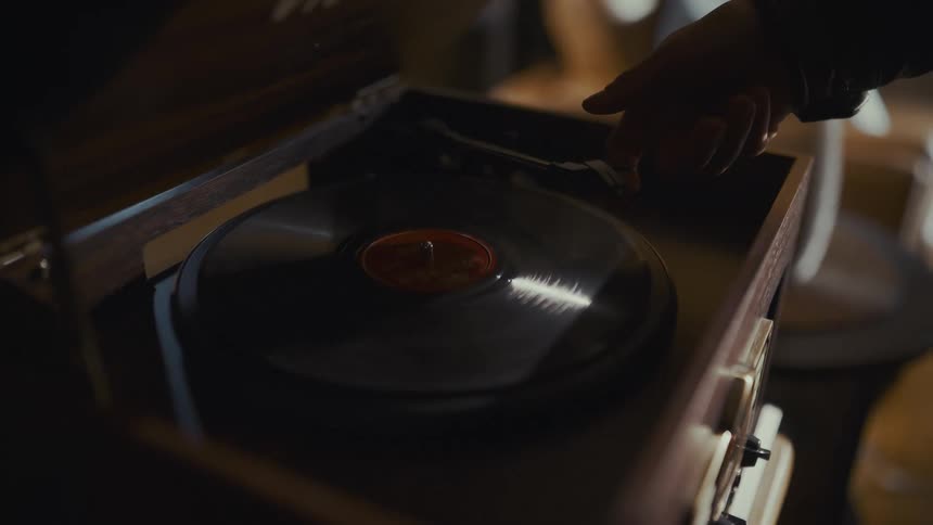 Slow motion shot of a man placing a vinyl record on a vintage record player to listen to music