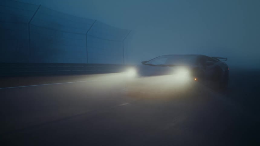 A dark sports car sits parked on a foggy racetrack at night, its bright headlights illuminating the mysterious, moody atmosphere as the camera pulls back