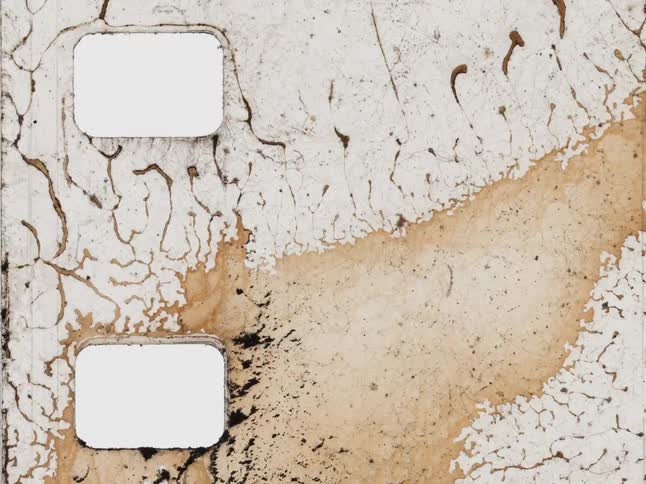 Close-up detail of an old, damaged film strip burning and melting in a stop-motion sequence
