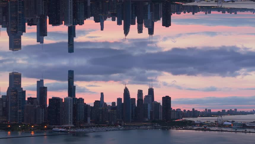 A surreal mirrored cityscape of Chicago reflects itself against a beautiful sunset sky over the water