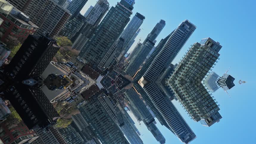 A surreal vertical view reveals a dizzying kaleidoscope of a modern cityscape pulling away under a clear blue sky
