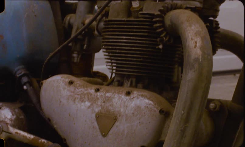 Vintage film captures a detailed close-up of a weathered and forgotten classic motorcycle engine