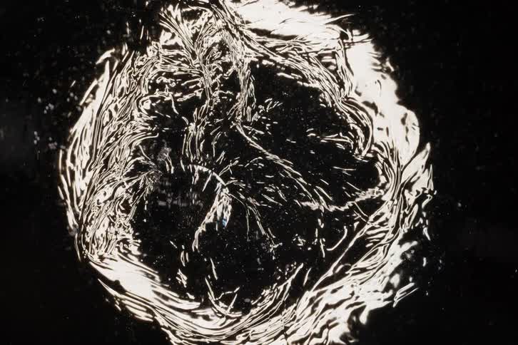 A mesmerizing close-up of a viscous black and silver liquid swirling and evolving to create abstract patterns