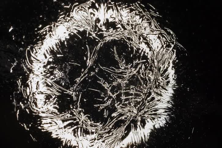 Liquid silver abstract art created by mesmerizing ripples and waves in slow motion on a black background