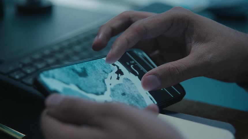 A medical professional analyzes a CT scan of a human brain on a smartphone screen in a dark room