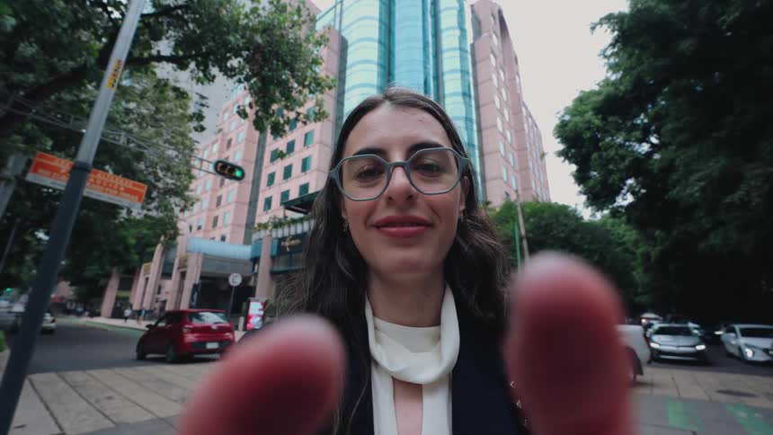 First-person perspective of a young businesswoman smiling gently at the camera while standing on a busy city street