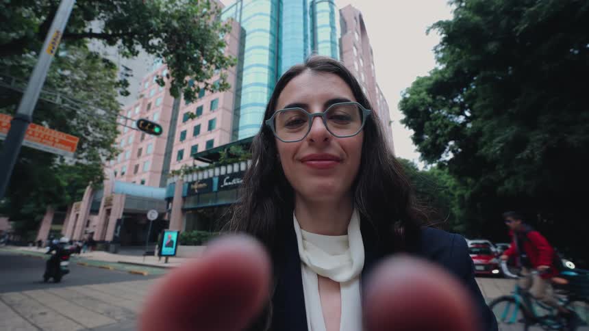 A cinemagraph shows a woman's point-of-view as she holds her camera for a selfie on a busy city street, with her fingers blurred in the foreground
