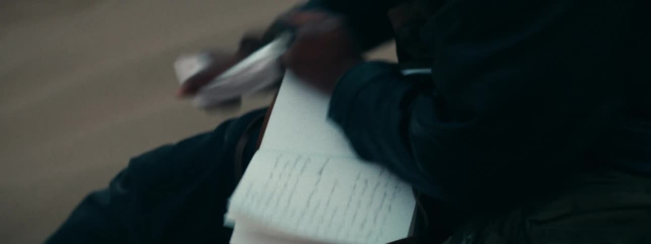 A close-up view of a person's hands angrily ripping out handwritten pages from a journal and crumpling them